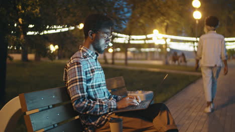 Afroamerikanischer-Mann,-Der-Abends-Im-Park-Am-Laptop-Arbeitet